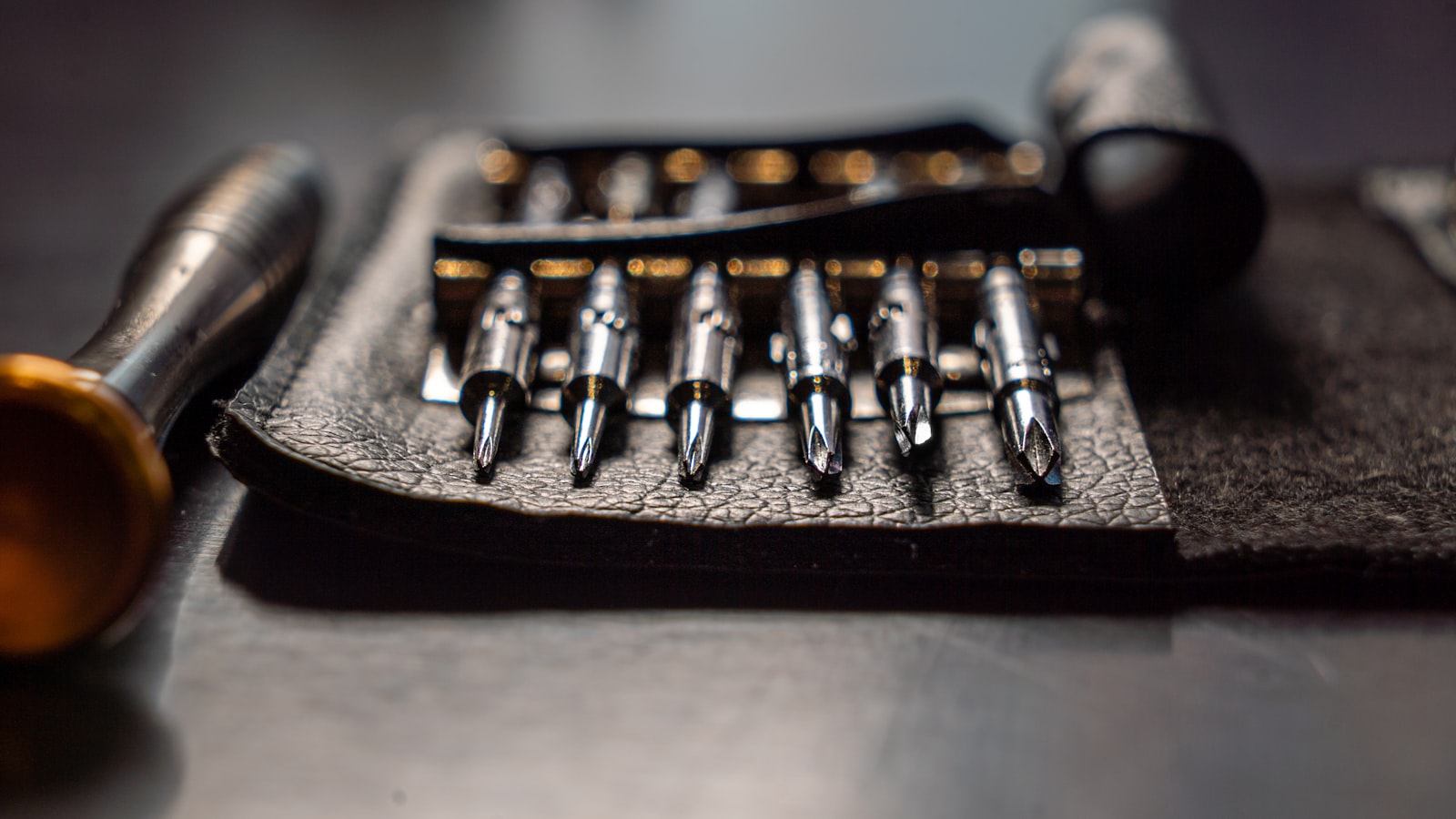 A set of screwdriver bits laid out on a leather tool roll.