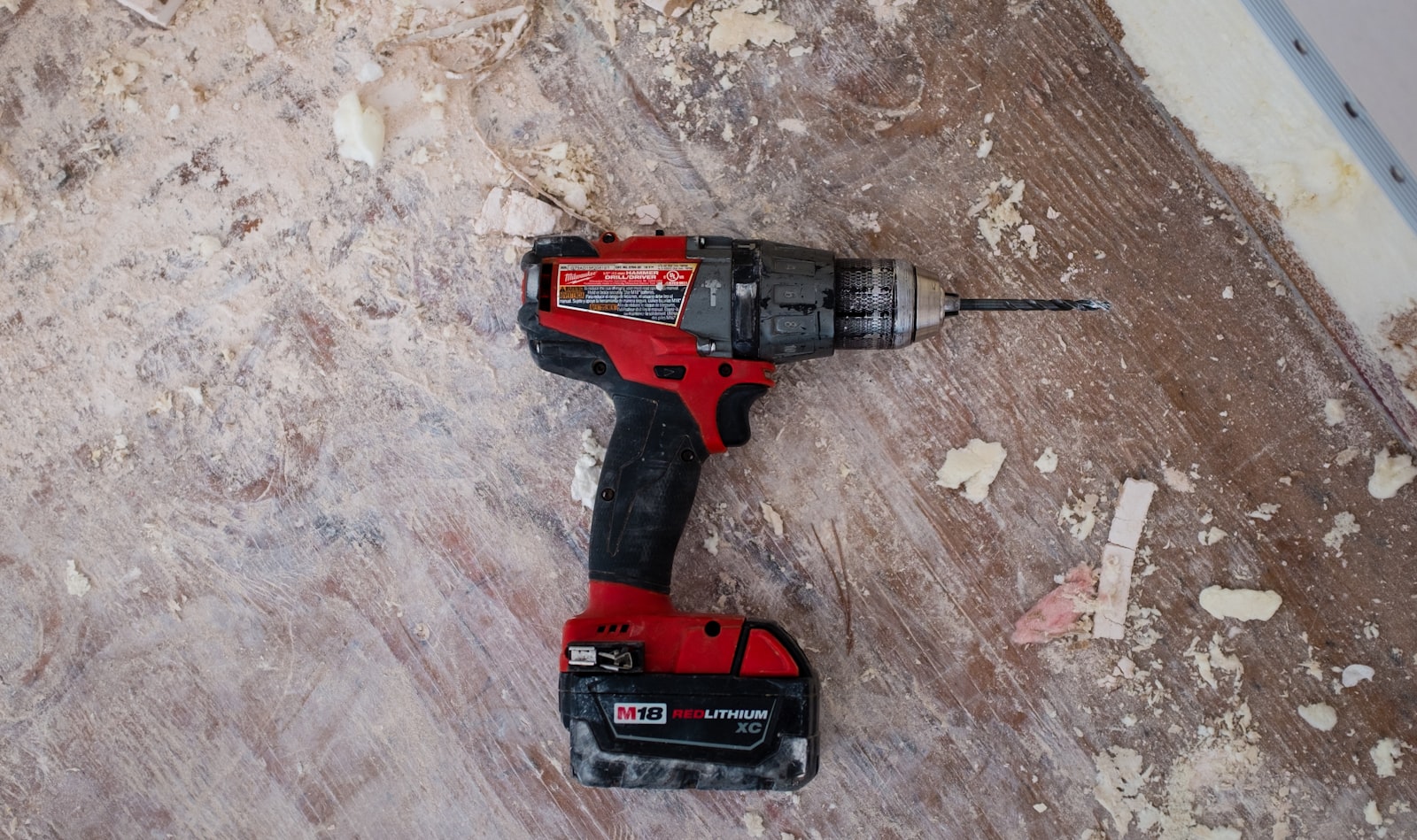 A cordless drill resting on a subfloor during a home renovation.
